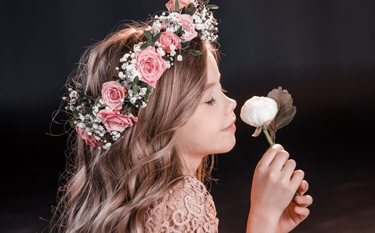 portret dziewczynki z wiankiem kwiatów na głowie wąchającej białą piwonię